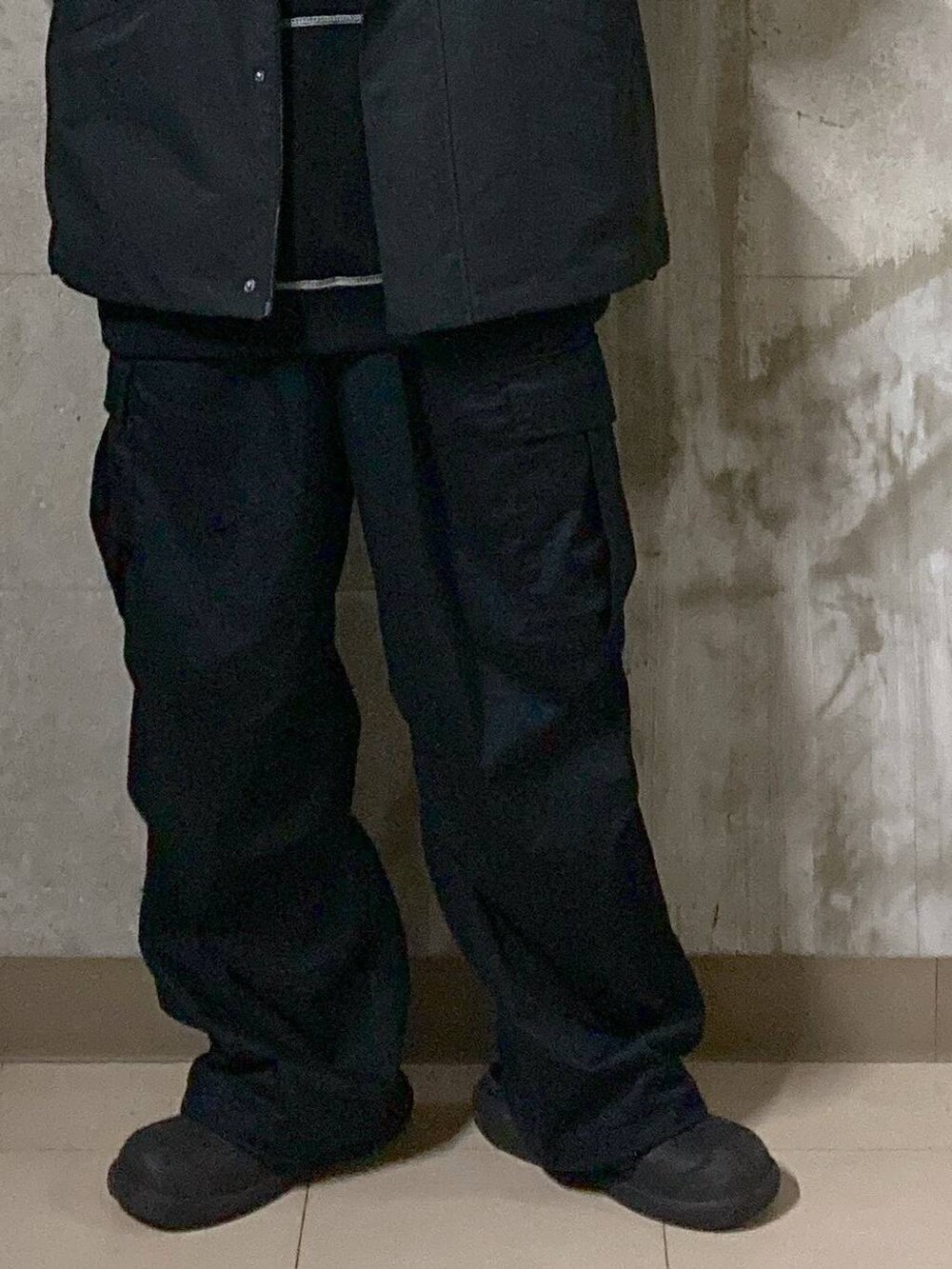 ブラック系のTシャツ/カットソー、ブラック系のカーゴパンツ、ブラック系のブルゾンを着用したメンズの秋コーディネートの6枚目の写真