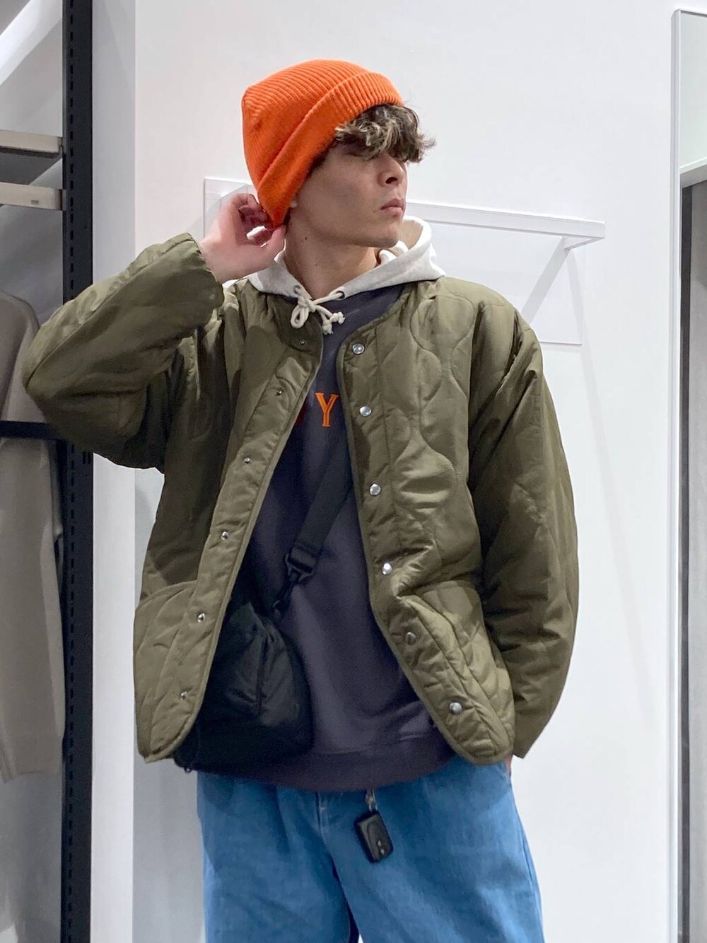 ホワイト系のパーカー、ブラック系のショルダーバッグ、グリーン系のブルゾンを着用したメンズの冬コーディネートの8枚目の写真