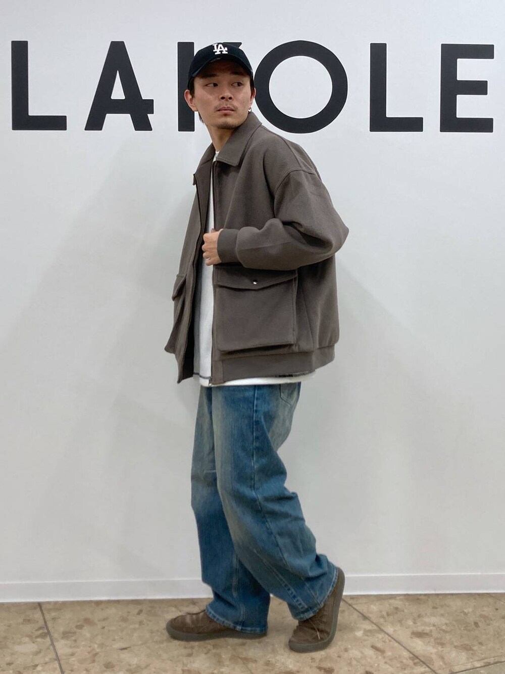 ブラウン系のブルゾン、ブルー系のデニムパンツ、ホワイト系のTシャツ/カットソーを着用したメンズの秋コーディネートの3枚目の写真
