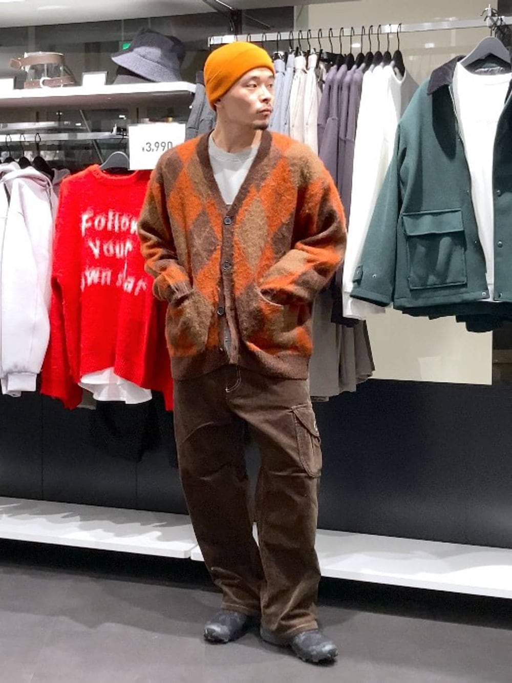 ブラウン系のその他パンツ、ブラウン系のカーディガン/ボレロ、オレンジ系のニットキャップ/ビーニーを着用したメンズの冬コーディネートの5枚目の写真