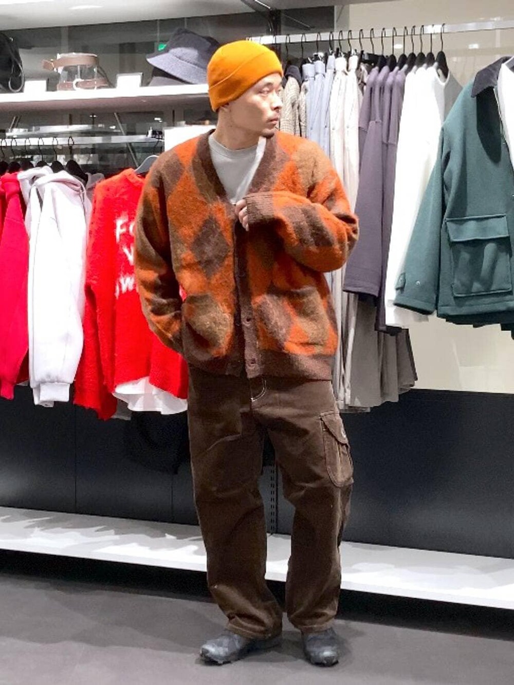 ブラウン系のその他パンツ、ブラウン系のカーディガン/ボレロ、オレンジ系のニットキャップ/ビーニーを着用したメンズの冬コーディネートの7枚目の写真