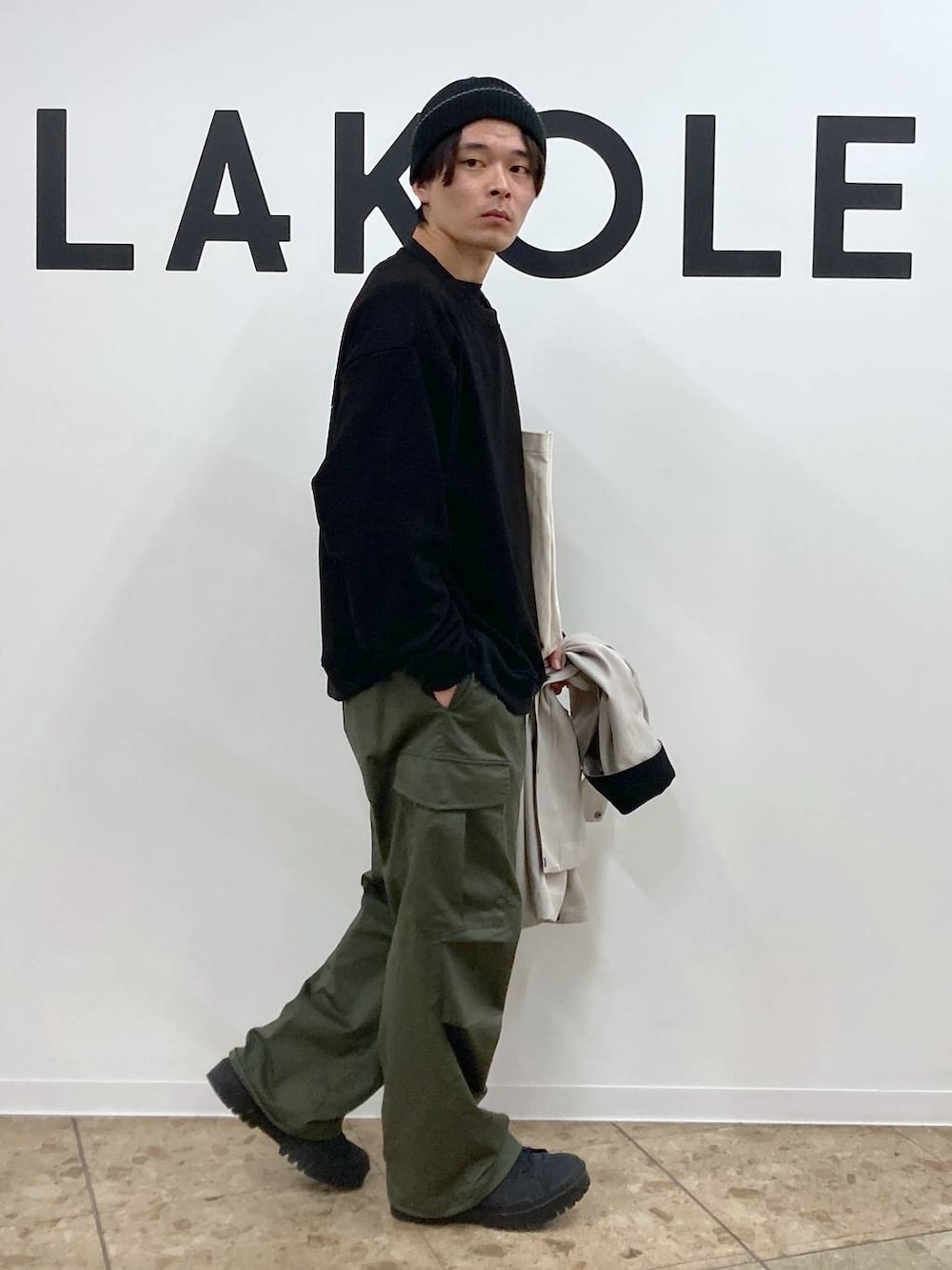 ベージュ系のトートバッグ、ブラック系のその他トップス、グリーン系のカーゴパンツを着用したメンズの冬コーディネートの8枚目の写真