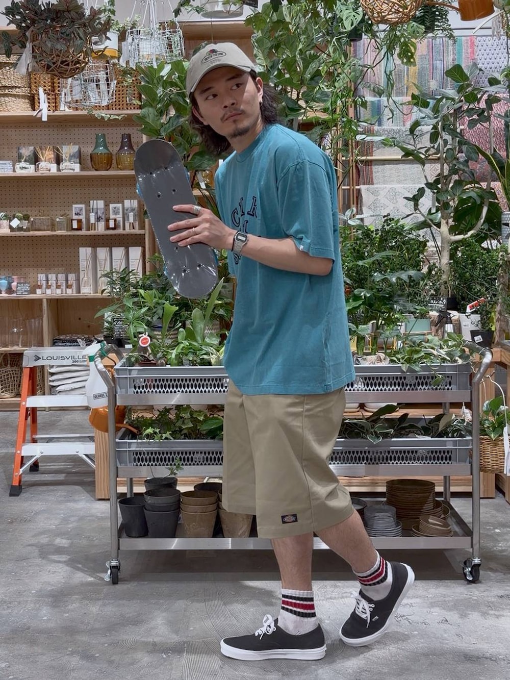 グリーン系のTシャツ/カットソー、ブルー系のスポーツグッズ、ベージュ系のキャップを着用したメンズの夏コーディネートの3枚目の写真
