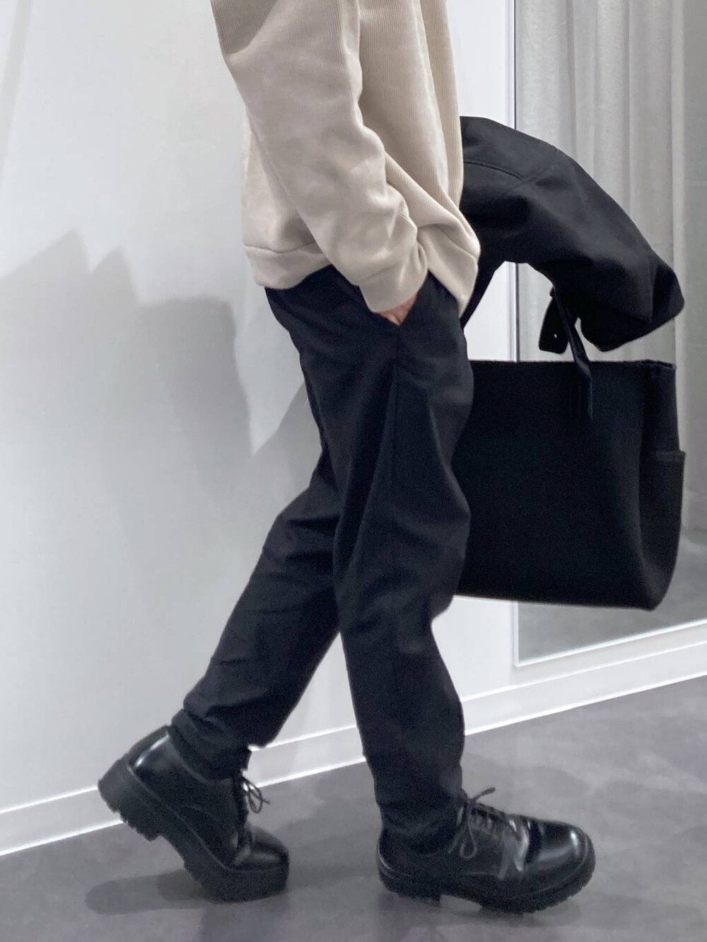 ブラック系のステンカラーコート、ブラック系のトートバッグ、ブラック系のドレスシューズを着用したメンズの冬コーディネートの7枚目の写真