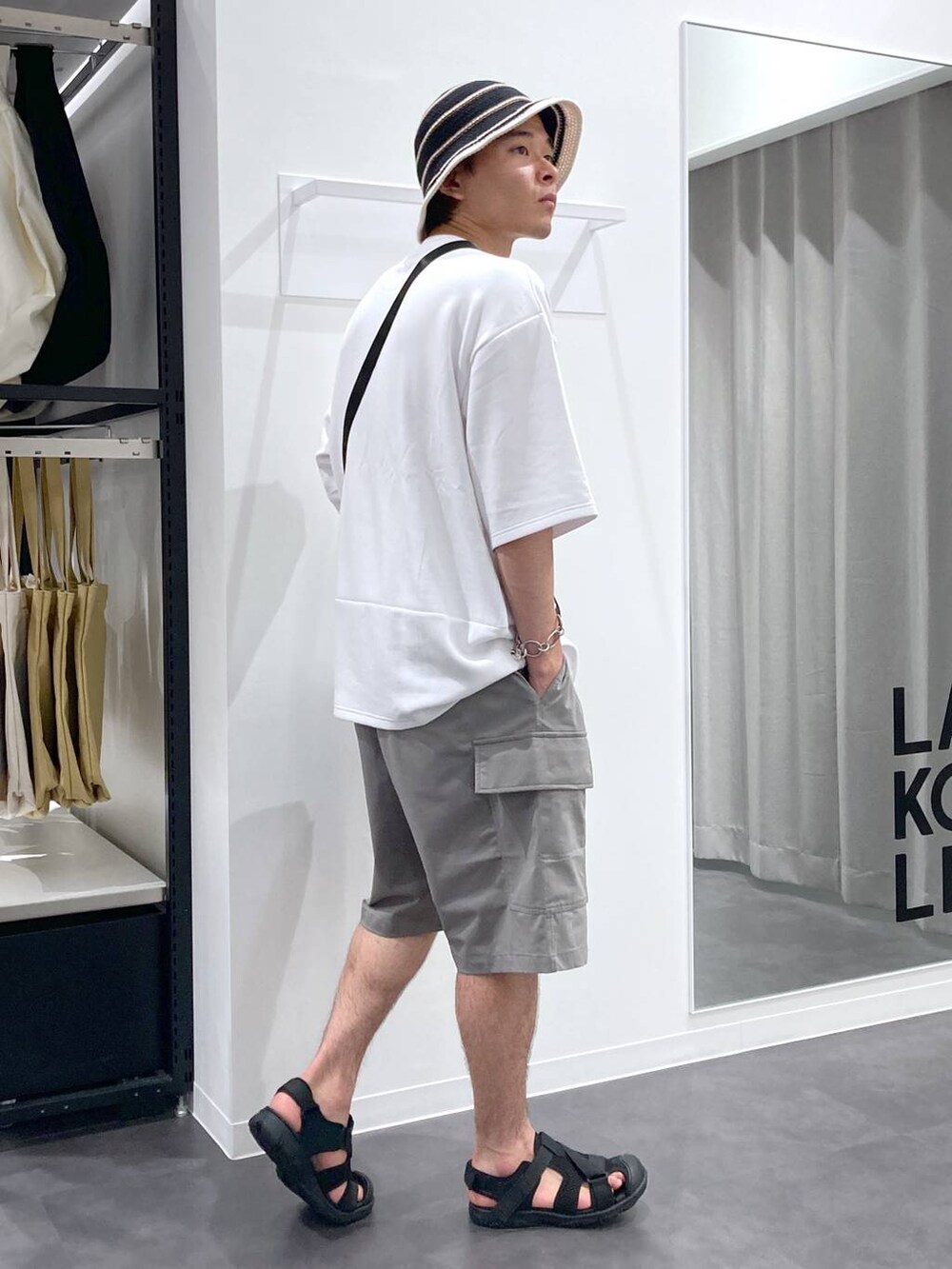 ブラック系のサンダル、ホワイト系のTシャツ/カットソー、ブラック系のショルダーバッグを着用したメンズの夏コーディネートの3枚目の写真