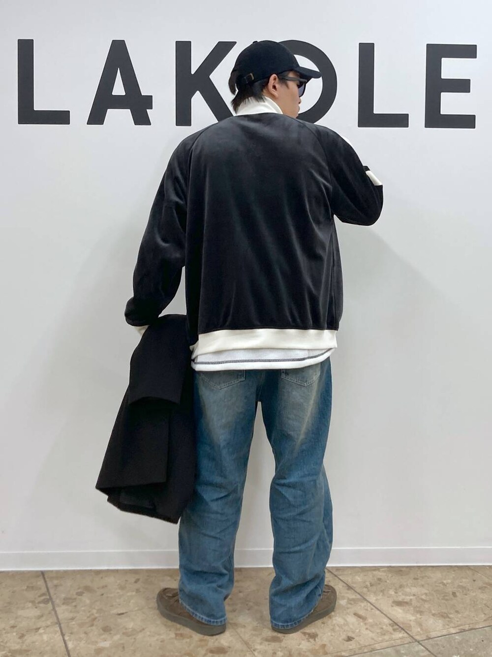 ブラック系のチェスターコート、ブルー系のデニムパンツ、ホワイト系のTシャツ/カットソーを着用したメンズの秋コーディネートの6枚目の写真