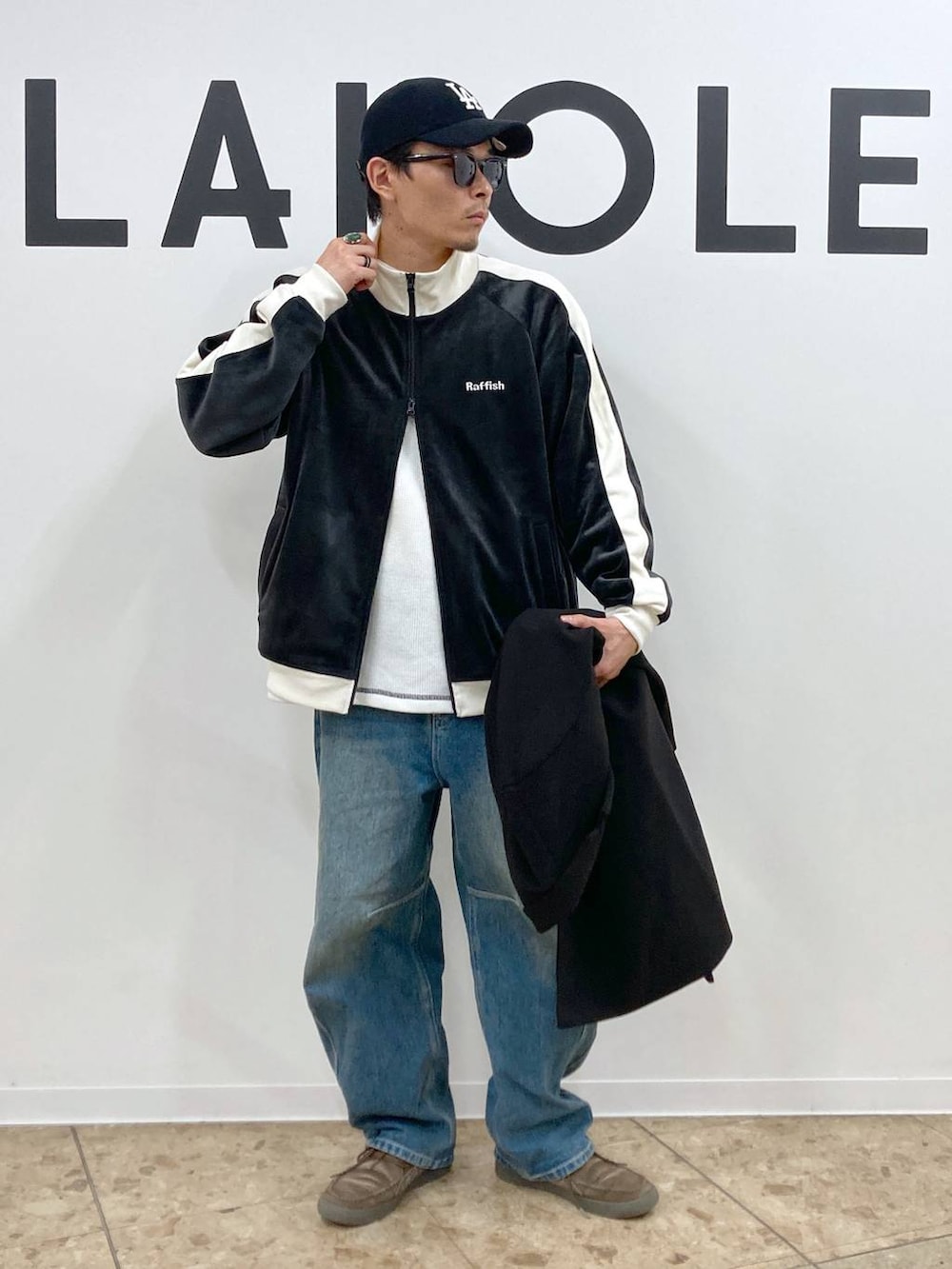ブラック系のチェスターコート、ブルー系のデニムパンツ、ホワイト系のTシャツ/カットソーを着用したメンズの秋コーディネートの5枚目の写真
