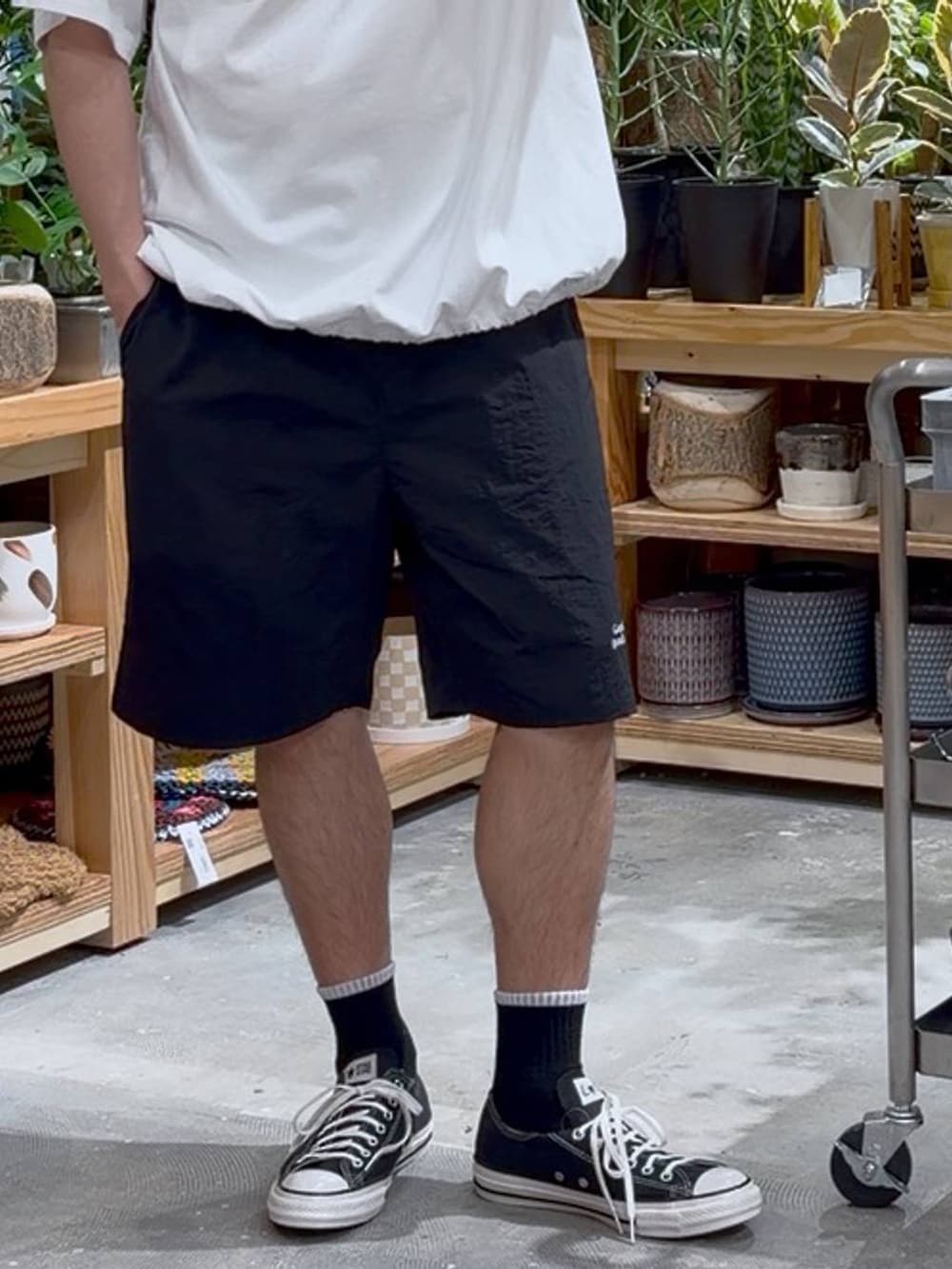 ブラック系のスニーカー、オレンジ系のバックパック/リュック、ホワイト系のTシャツ/カットソーを着用したメンズの春コーディネートの6枚目の写真