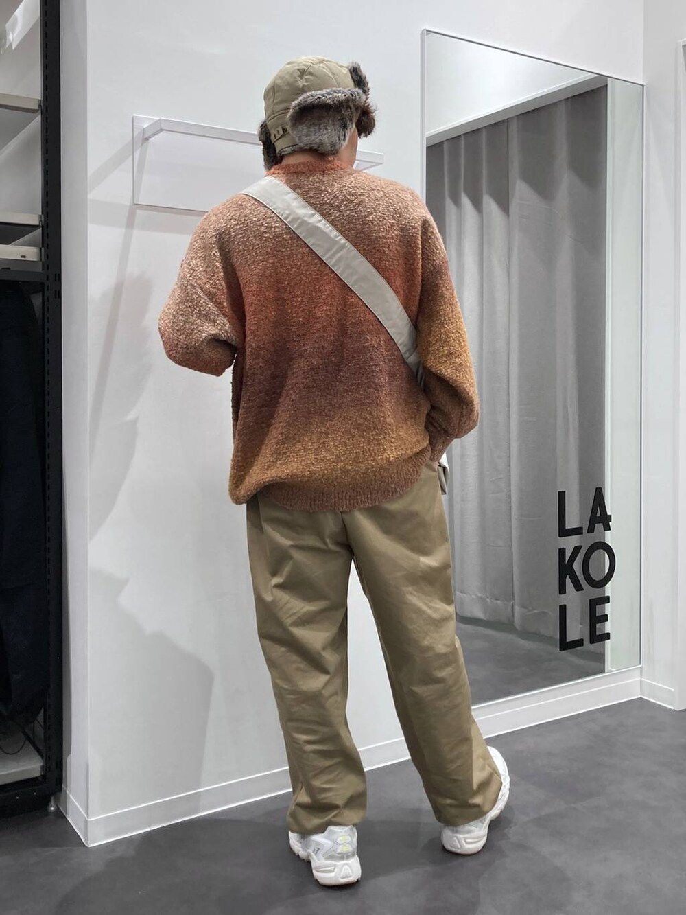 ホワイト系のスニーカー、オレンジ系のニット/セーター、ベージュ系のチノパンツを着用したメンズの秋コーディネートの9枚目の写真