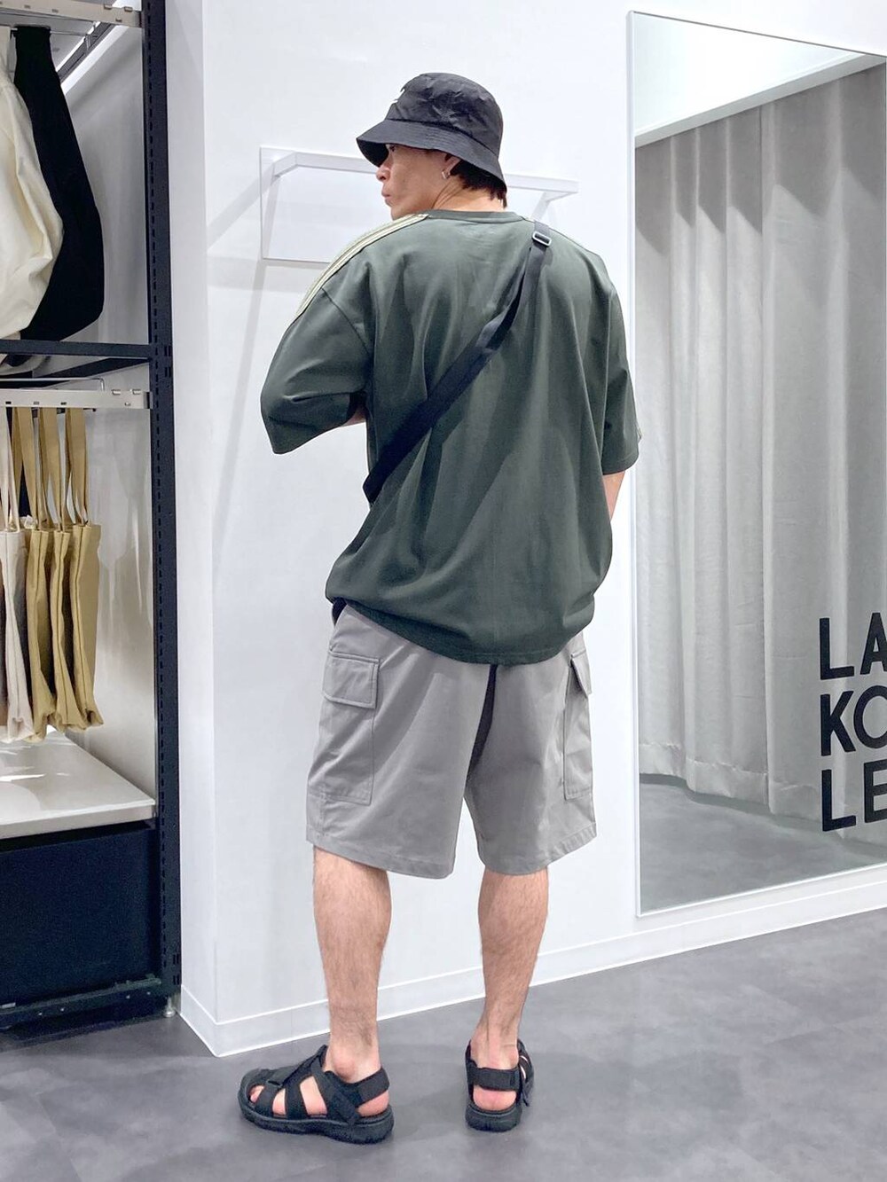 ブラック系のショルダーバッグ、ブラック系のサンダル、グリーン系のTシャツ/カットソーを着用したメンズの夏コーディネートの2枚目の写真