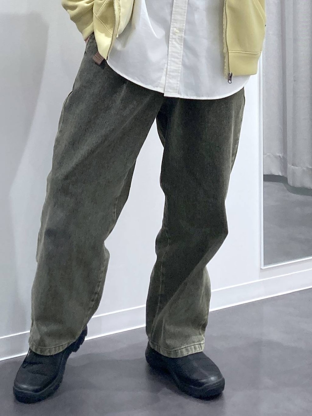 ブラック系のスリッポン、グリーン系のデニムパンツ、イエロー系のパーカーを着用したメンズの冬コーディネートの9枚目の写真