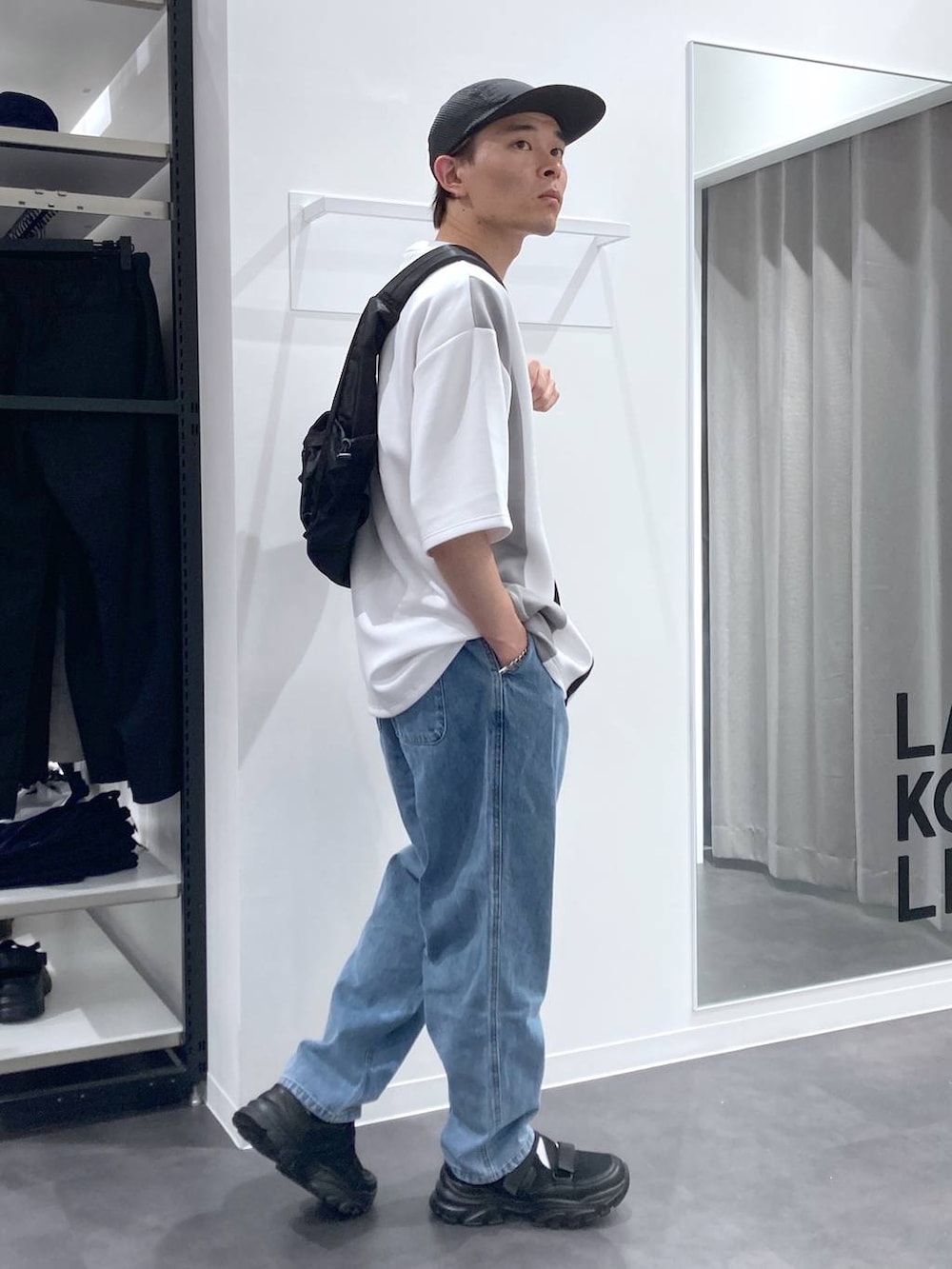 ブラック系のスニーカー、ブラック系のショルダーバッグ、ブルー系のデニムパンツを着用したメンズの夏コーディネートの4枚目の写真