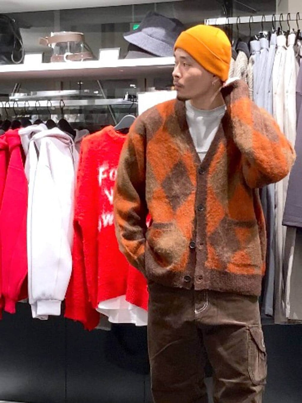 ブラウン系のその他パンツ、ブラウン系のカーディガン/ボレロ、オレンジ系のニットキャップ/ビーニーを着用したメンズの冬コーディネートの6枚目の写真
