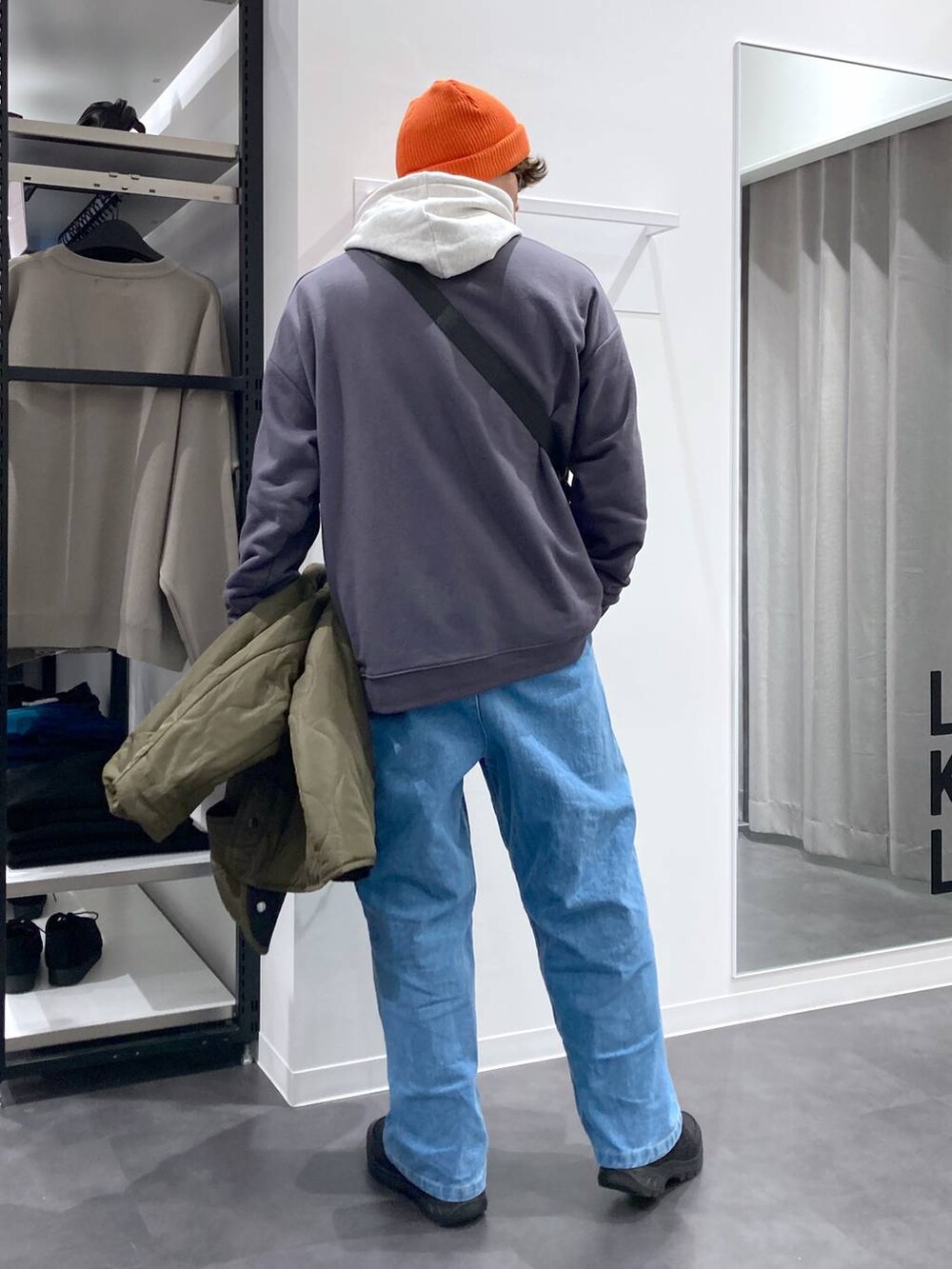 ホワイト系のパーカー、ブラック系のショルダーバッグ、グリーン系のブルゾンを着用したメンズの冬コーディネートの6枚目の写真