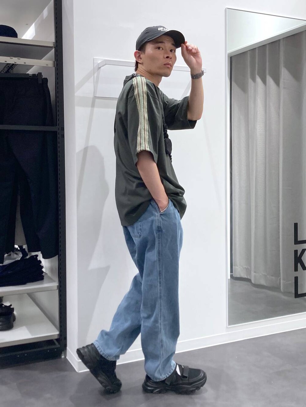 ブラック系のスニーカー、ブラック系のショルダーバッグ、ブルー系のデニムパンツを着用したメンズの夏コーディネートの4枚目の写真