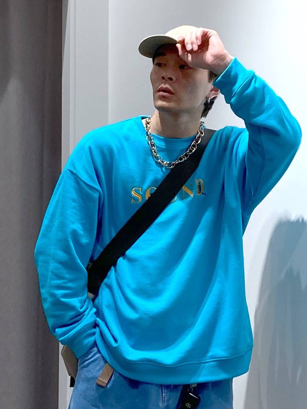 グレー系のスニーカー、ベージュ系のメッセンジャーバッグ、ブルー系のデニムパンツを着用したメンズの冬コーディネートの6枚目の写真