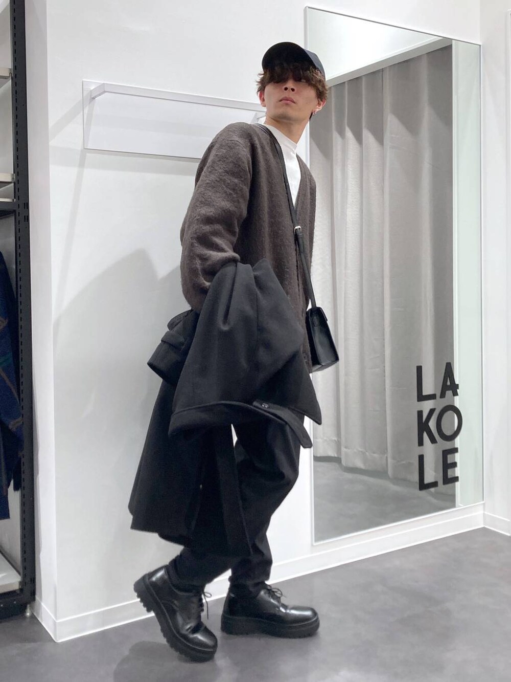 ブラック系のトレンチコート、グレー系のTシャツ/カットソー、ホワイト系のスウェットを着用したメンズの冬コーディネートの7枚目の写真