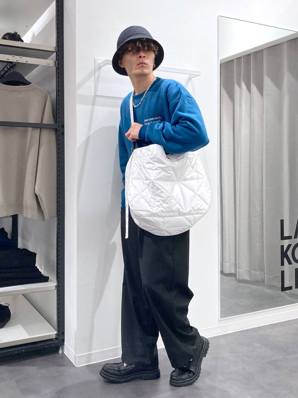 ブラック系のローファー、グリーン系のスウェット、ホワイト系のショルダーバッグを着用したメンズの冬コーディネートの3枚目の写真