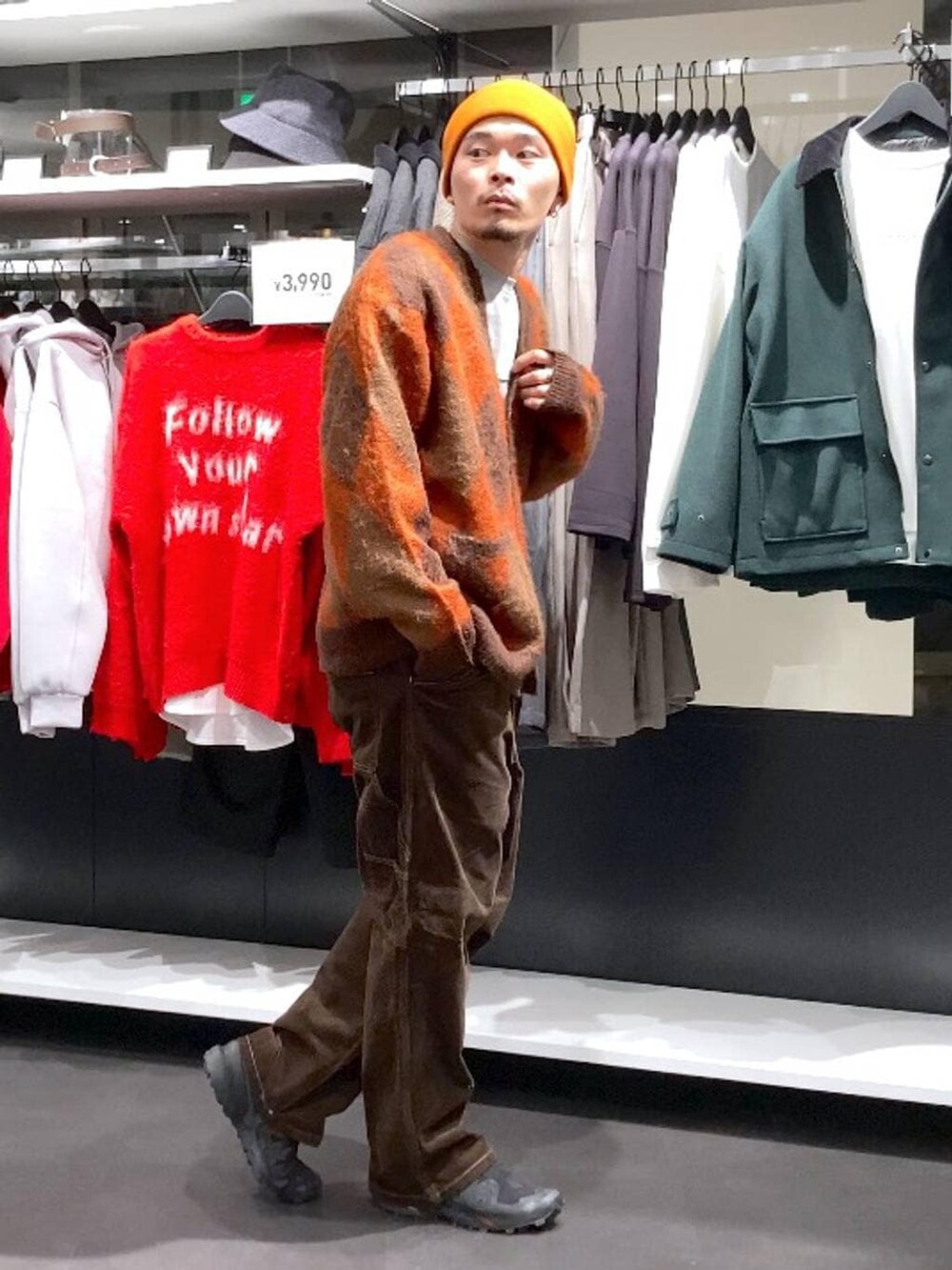 ブラウン系のその他パンツ、ブラウン系のカーディガン/ボレロ、オレンジ系のニットキャップ/ビーニーを着用したメンズの冬コーディネートの3枚目の写真