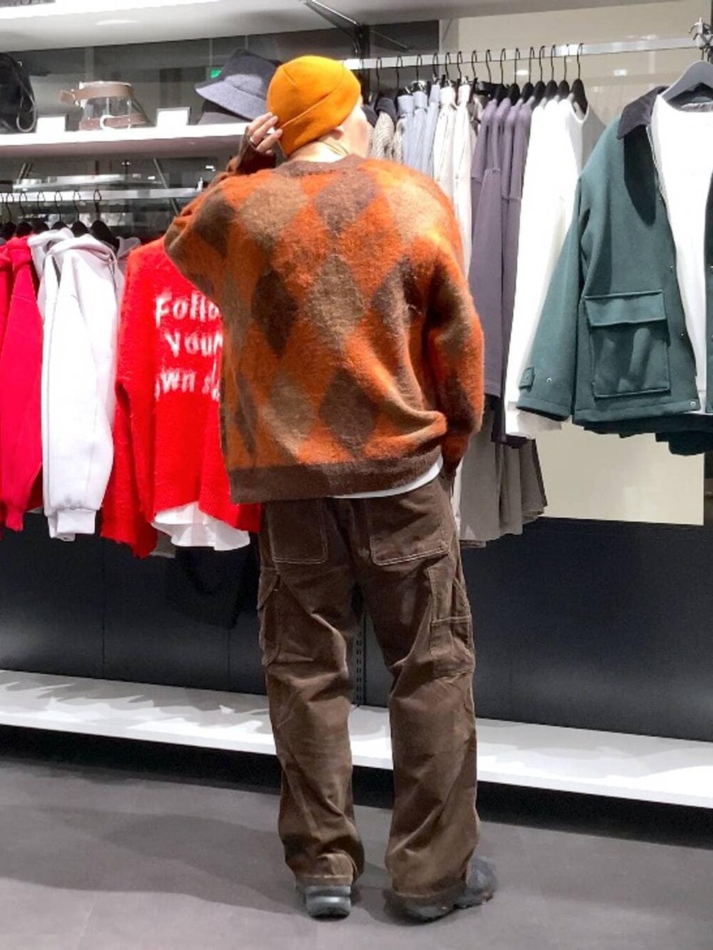 ブラウン系のその他パンツ、ブラウン系のカーディガン/ボレロ、オレンジ系のニットキャップ/ビーニーを着用したメンズの冬コーディネートの2枚目の写真