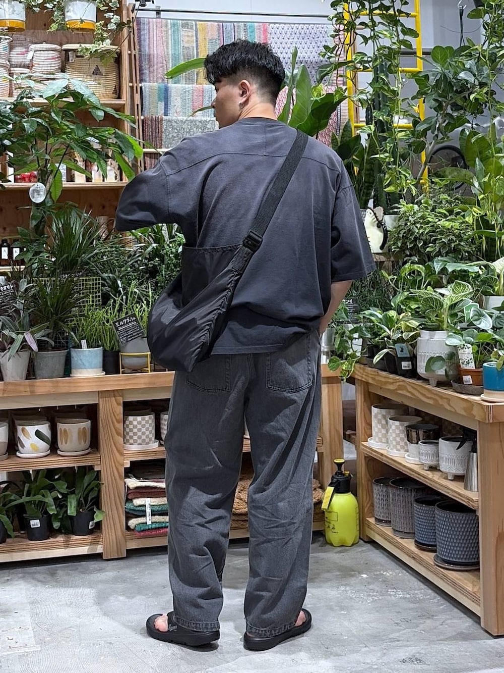 ブラック系のTシャツ/カットソー、ブラック系のエコバッグ/サブバッグ、ブラック系のサンダルを着用したメンズの夏コーディネートの2枚目の写真