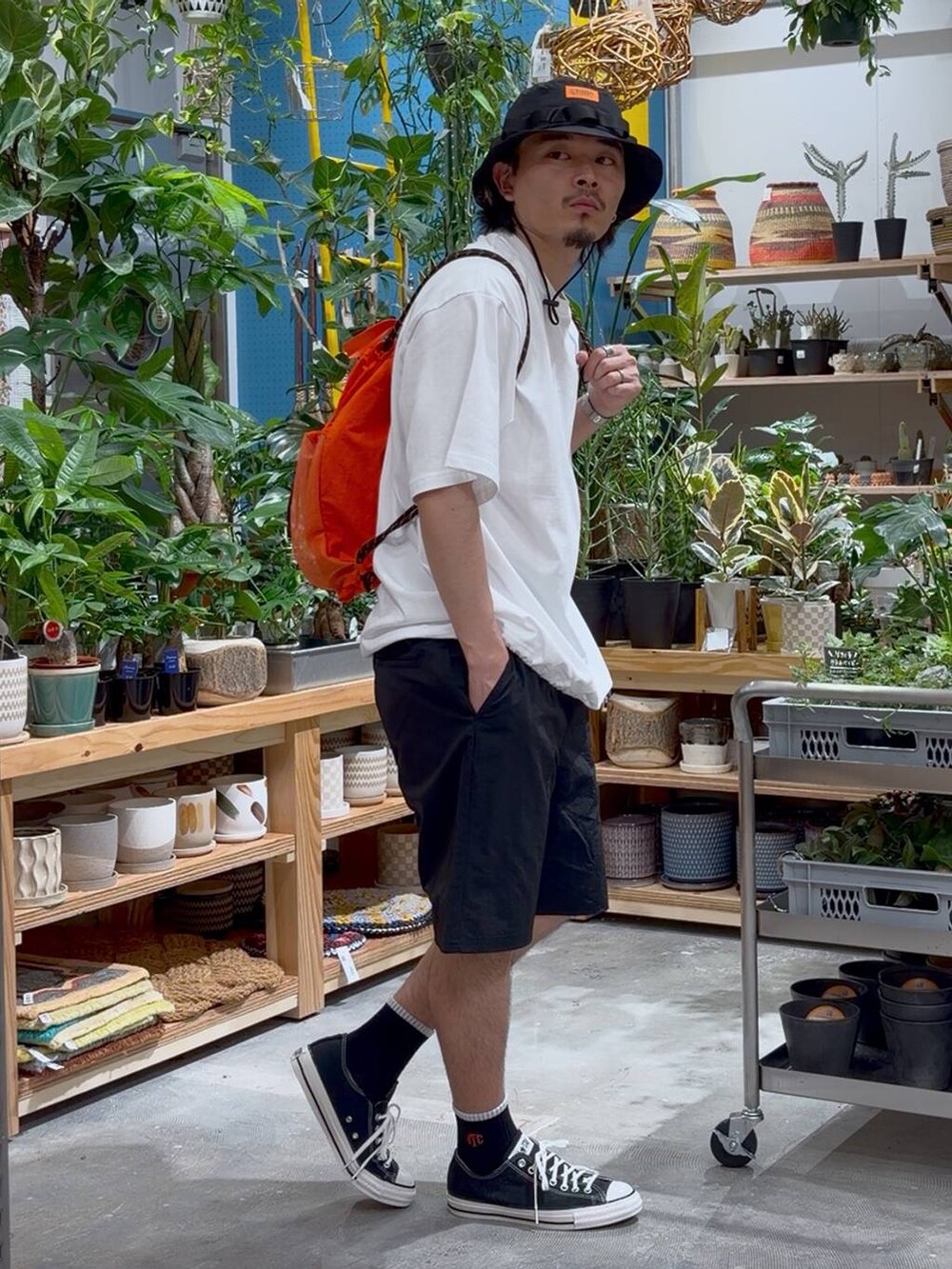 ブラック系のスニーカー、オレンジ系のバックパック/リュック、ホワイト系のTシャツ/カットソーを着用したメンズの春コーディネートの4枚目の写真