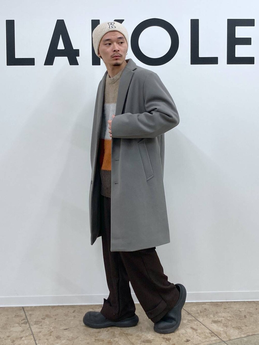 グレー系のチェスターコート、ブラウン系のカーゴパンツ、ブラウン系のニット/セーターを着用したメンズの冬コーディネートの3枚目の写真