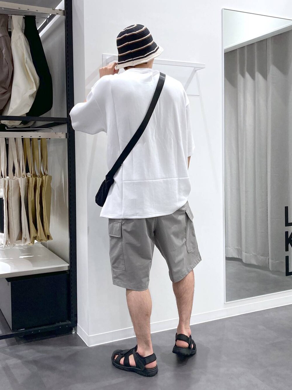 ブラック系のサンダル、ホワイト系のTシャツ/カットソー、ブラック系のショルダーバッグを着用したメンズの夏コーディネートの2枚目の写真