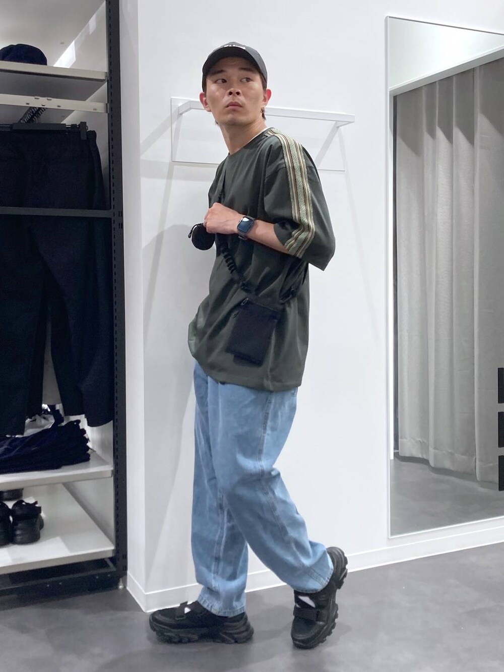 ブラック系のスニーカー、ブラック系のショルダーバッグ、ブルー系のデニムパンツを着用したメンズの夏コーディネートの3枚目の写真