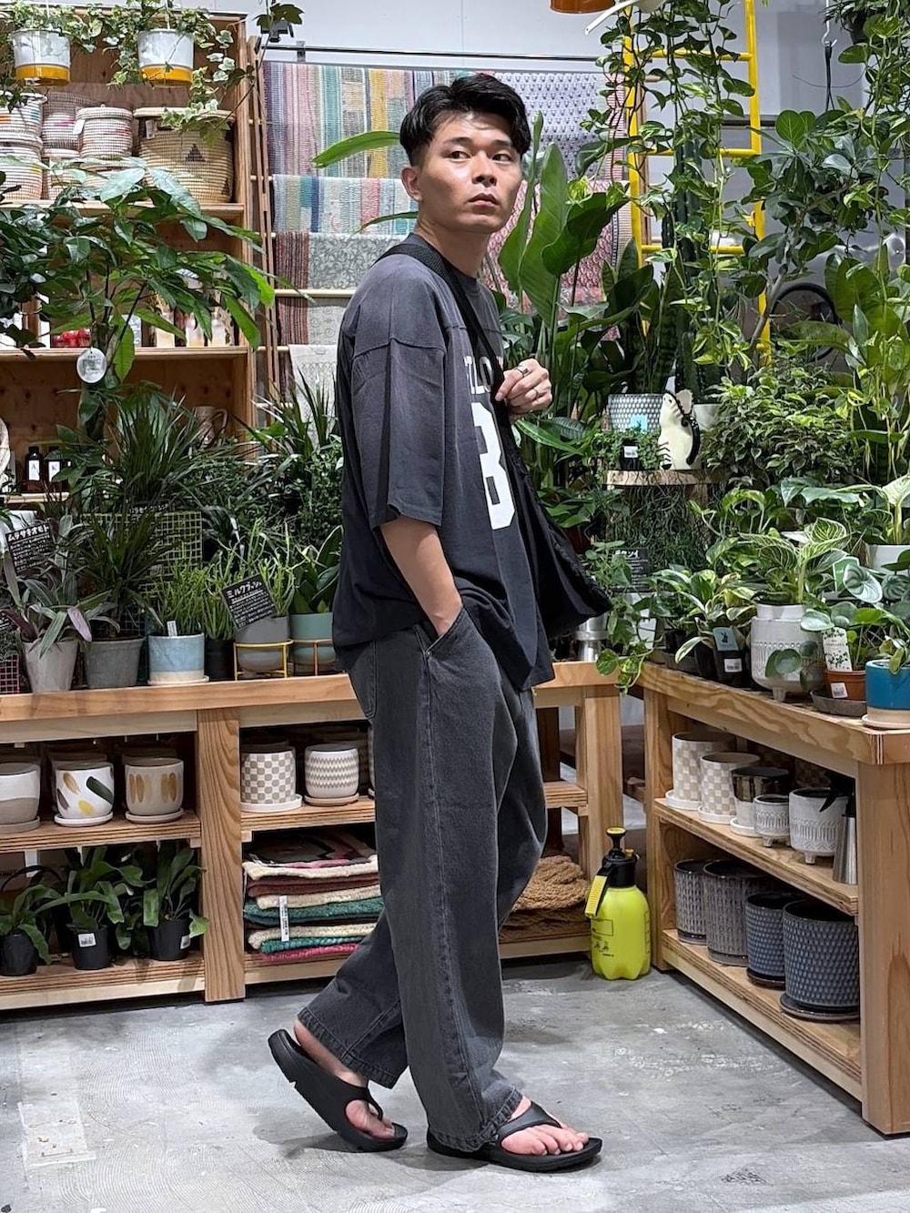 ブラック系のTシャツ/カットソー、ブラック系のエコバッグ/サブバッグ、ブラック系のサンダルを着用したメンズの夏コーディネートの3枚目の写真