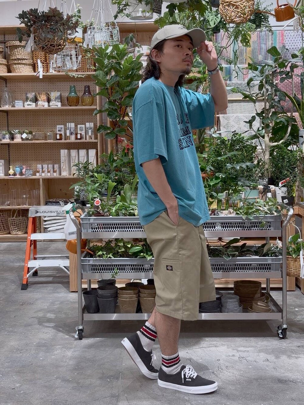 グリーン系のTシャツ/カットソー、ブルー系のスポーツグッズ、ベージュ系のキャップを着用したメンズの夏コーディネートの4枚目の写真