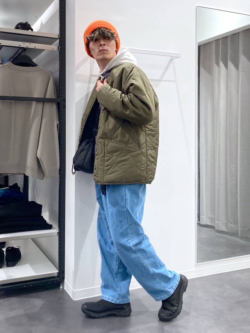 ホワイト系のパーカー、ブラック系のショルダーバッグ、グリーン系のブルゾンを着用したメンズの冬コーディネートの3枚目の写真