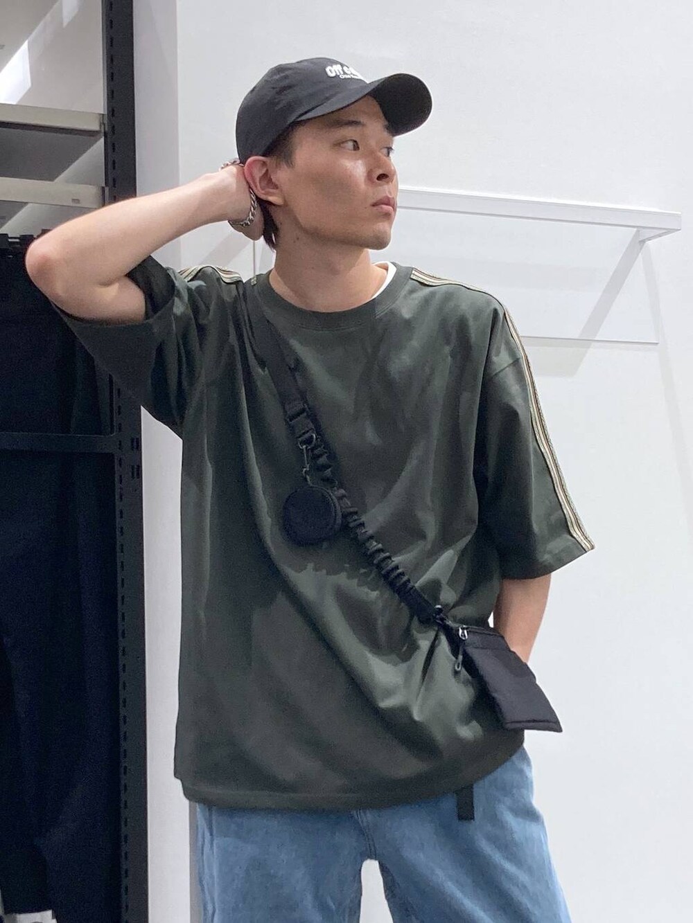 ブラック系のスニーカー、ブラック系のショルダーバッグ、ブルー系のデニムパンツを着用したメンズの夏コーディネートの6枚目の写真