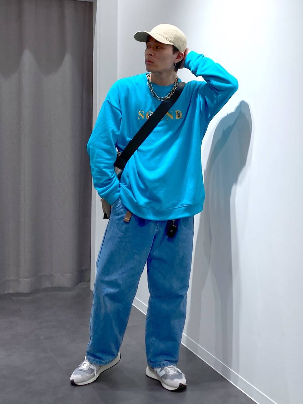 グレー系のスニーカー、ベージュ系のメッセンジャーバッグ、ブルー系のデニムパンツを着用したメンズの冬コーディネートの4枚目の写真