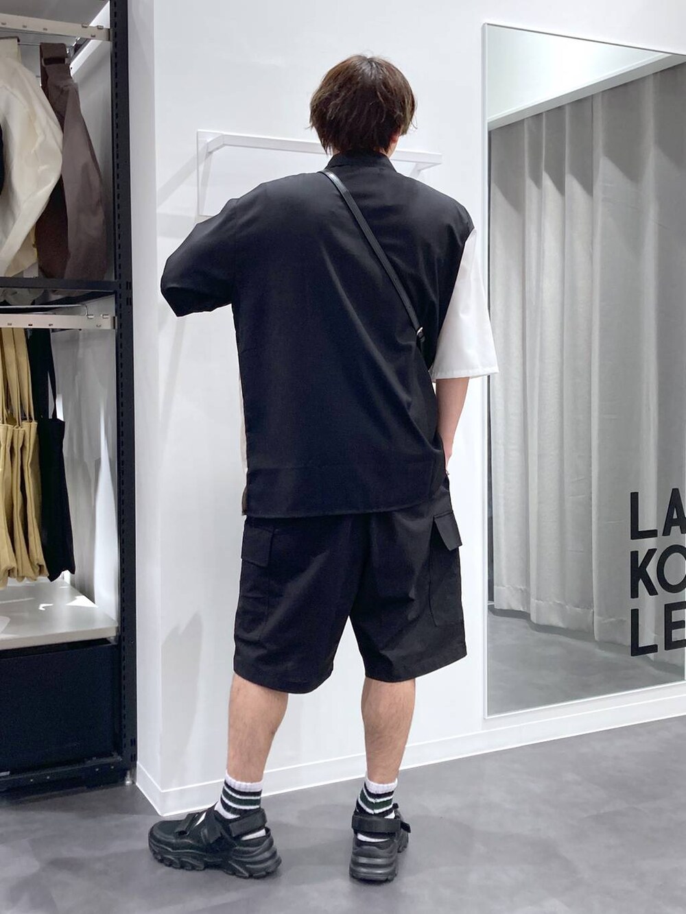 ブラック系のスニーカー、ホワイト系のTシャツ/カットソー、ブラック系のショルダーバッグを着用したメンズの夏コーディネートの2枚目の写真