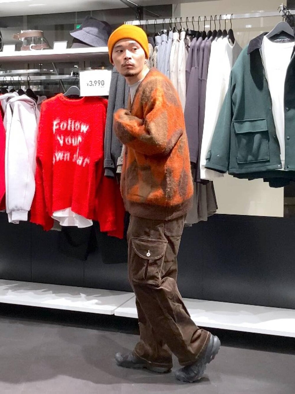 ブラウン系のその他パンツ、ブラウン系のカーディガン/ボレロ、オレンジ系のニットキャップ/ビーニーを着用したメンズの冬コーディネートの4枚目の写真