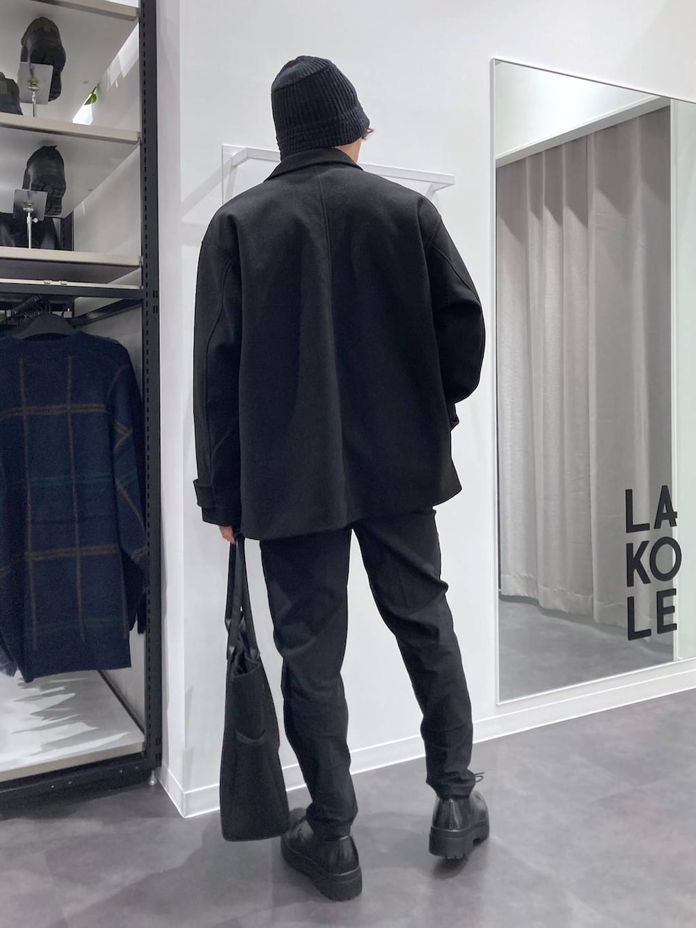 ブラック系のステンカラーコート、ブラック系のトートバッグ、ブラック系のドレスシューズを着用したメンズの冬コーディネートの2枚目の写真