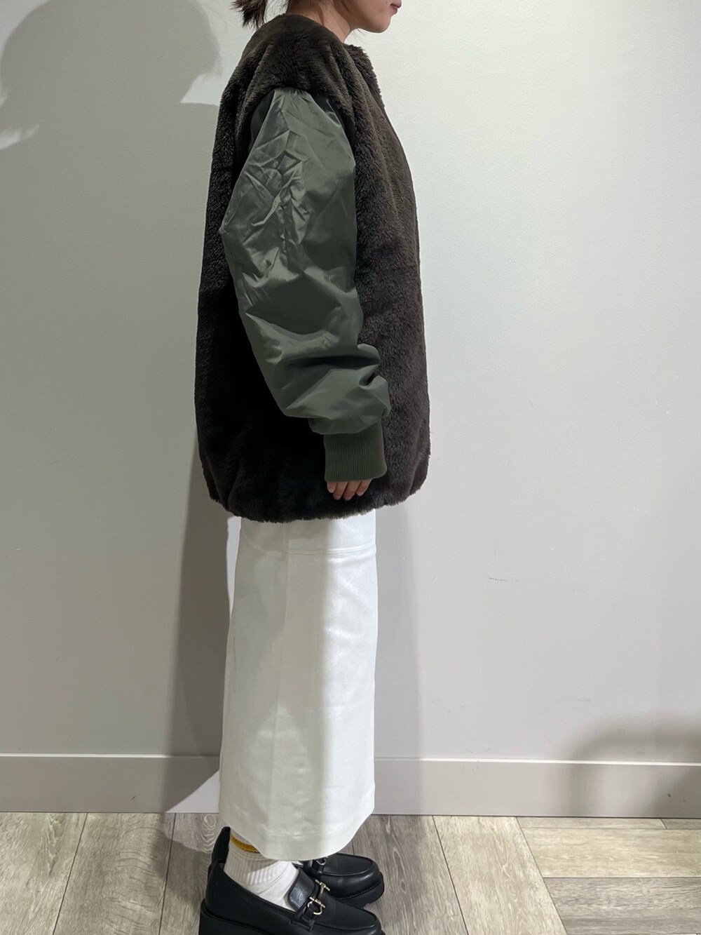 グリーン系のブルゾン、グレー系のTシャツ/カットソー、シルバー系のスカートを着用したレディースの秋コーディネートの3枚目の写真