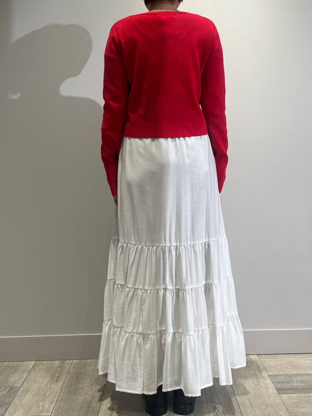 ホワイト系のスカート、ベージュ系のダウンジャケット/コート、レッド系のカーディガン/ボレロを着用したレディースの冬コーディネートの4枚目の写真