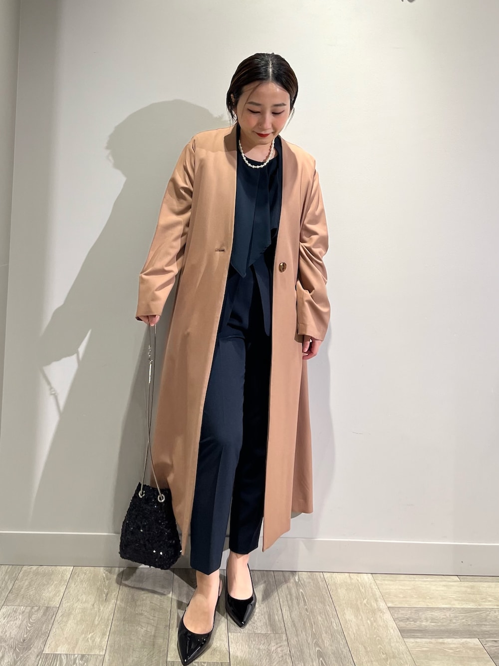 ベージュ系のノーカラーコート、ブルー系のセットアップ、ブルー系のスラックスを着用したレディースの冬コーディネートの6枚目の写真