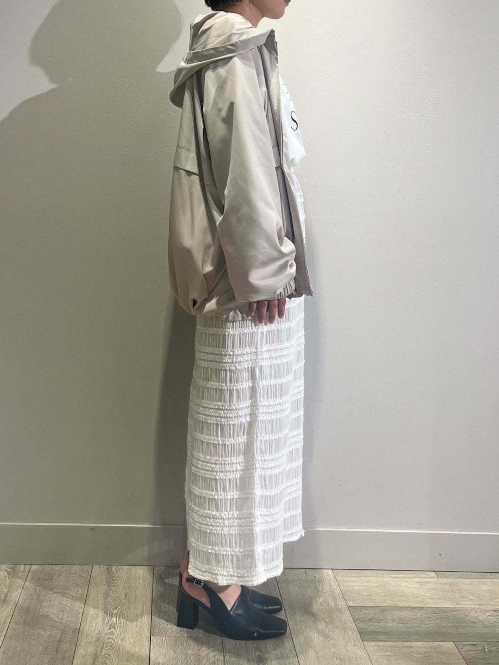 ホワイト系のスカート、ベージュ系のブルゾンを着用したレディースの夏コーディネートの3枚目の写真