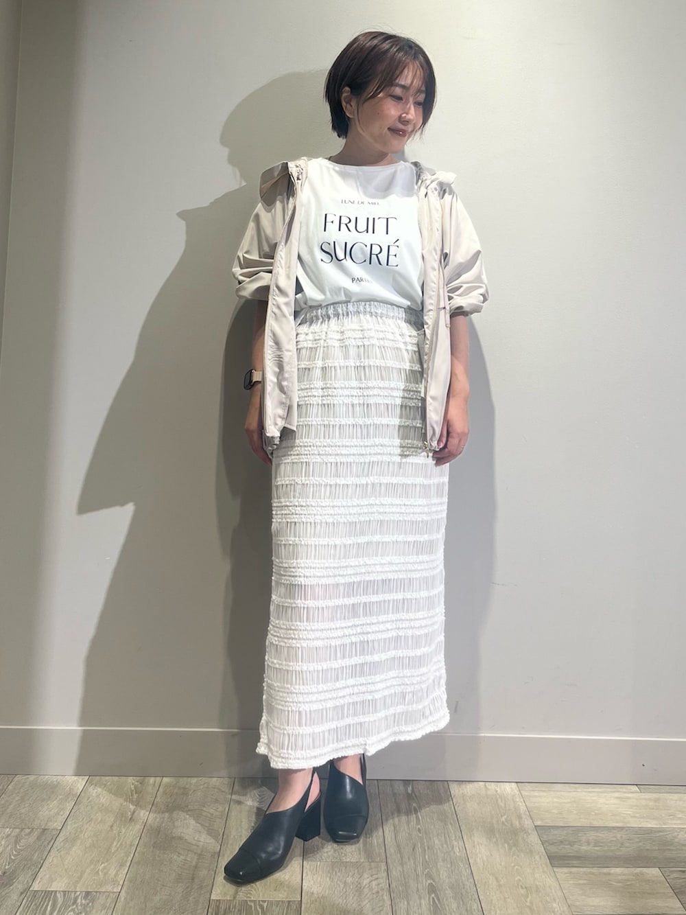 ホワイト系のスカート、ベージュ系のブルゾンを着用したレディースの夏コーディネートの2枚目の写真