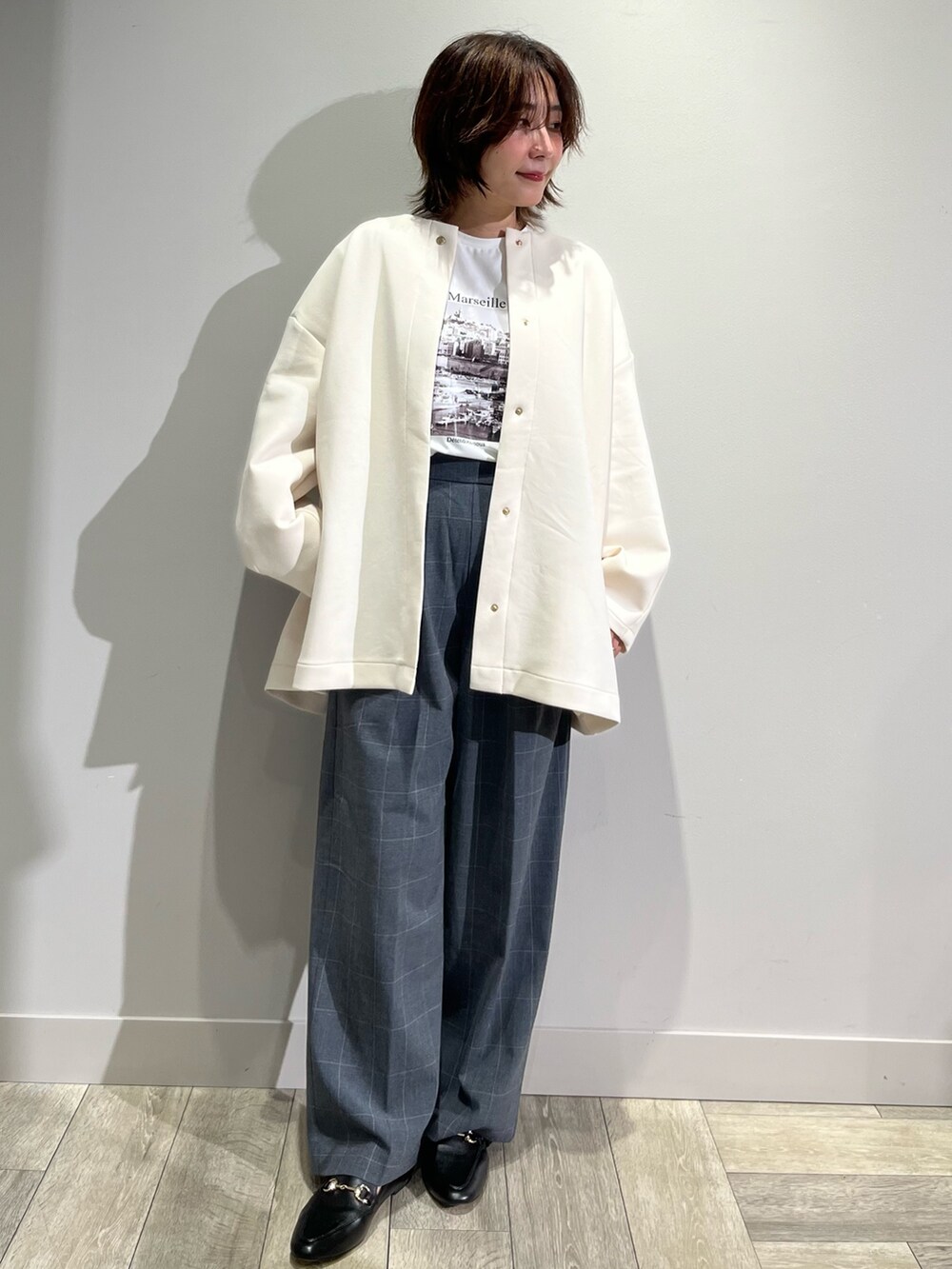 ホワイト系のノーカラーコート、グレー系のその他パンツ、ホワイト系のTシャツ/カットソーを着用したレディースの秋コーディネートの3枚目の写真