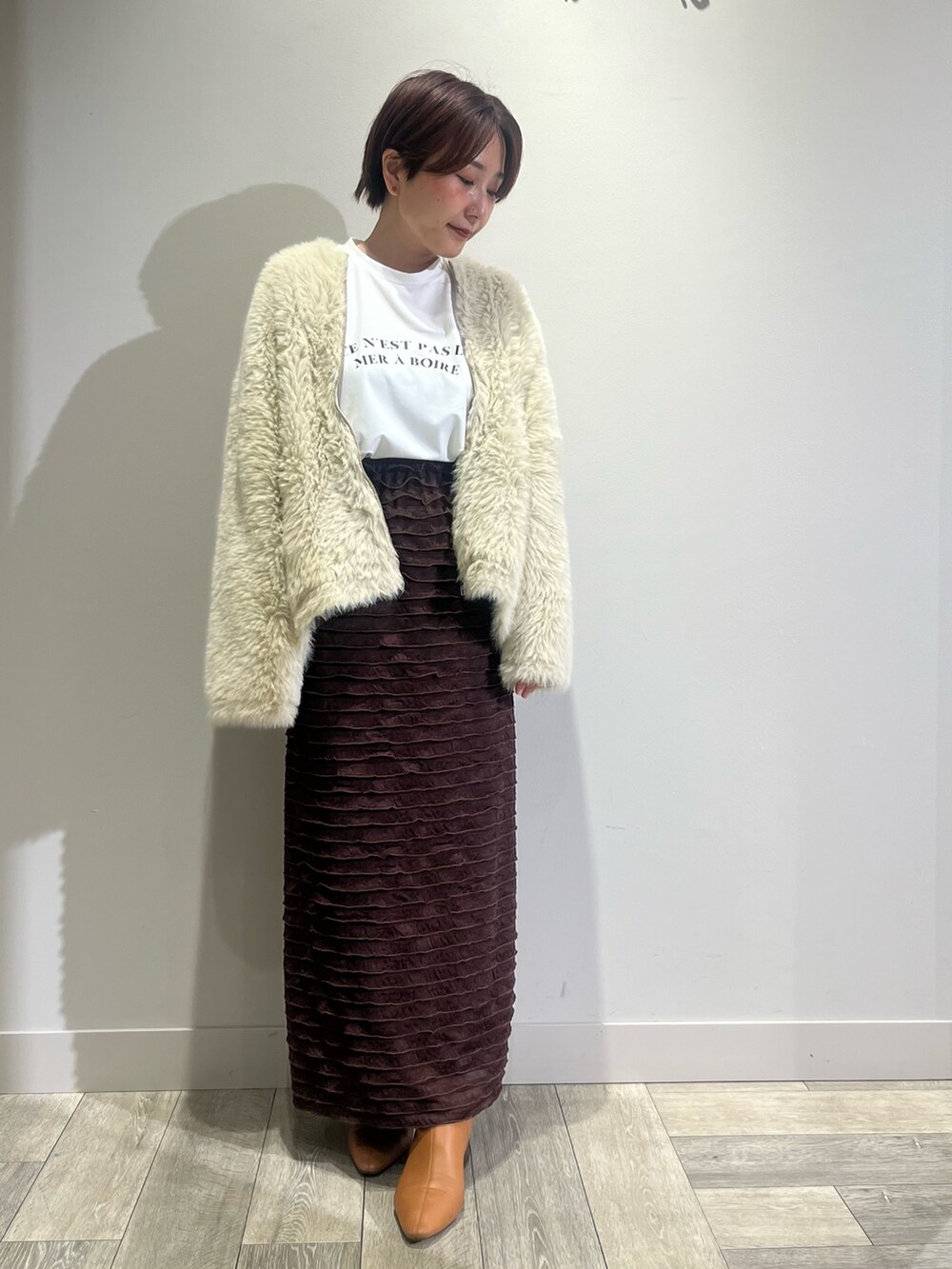 ホワイト系のカーディガン/ボレロ、ホワイト系のTシャツ/カットソー、ブラウン系のスカートを着用したレディースの秋コーディネートの2枚目の写真