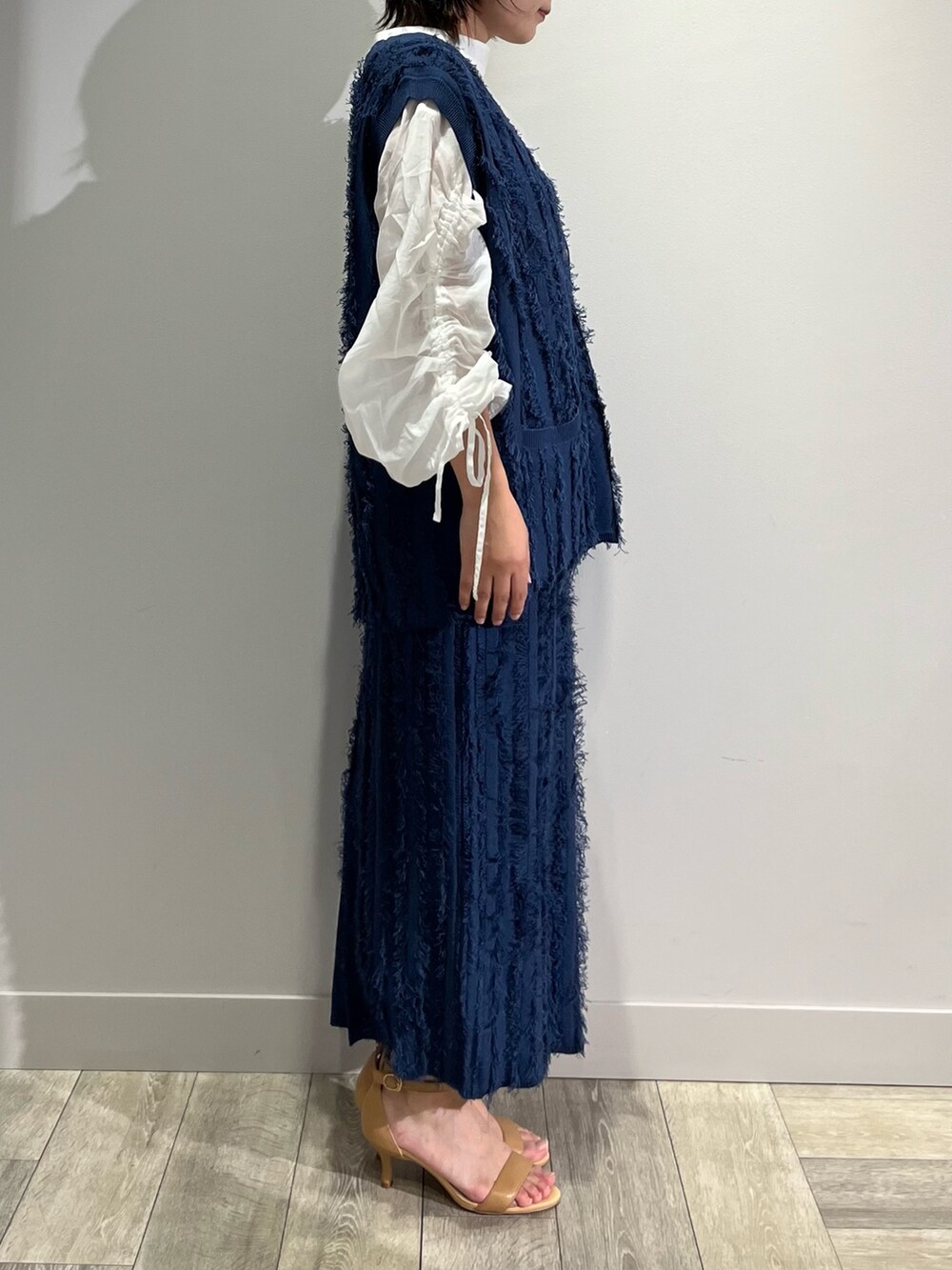 ブルー系のベスト、ブルー系のスカート、ホワイト系のシャツ/ブラウスを着用したレディースの秋コーディネートの2枚目の写真