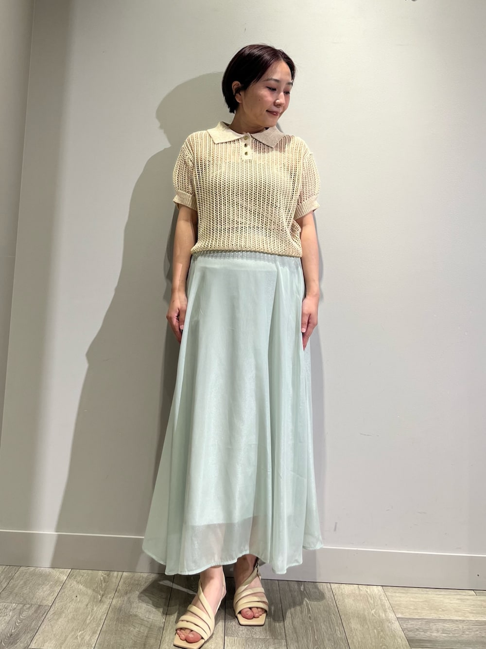 グリーン系のスカート、ベージュ系のニット/セーター、ベージュ系のサンダルを着用したレディースの夏コーディネートの2枚目の写真