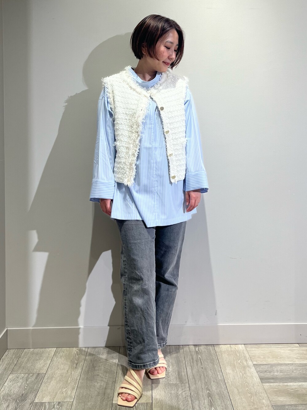 ブルー系のシャツ/ブラウス、ブラック系のデニムパンツ、ホワイト系のベストを着用したレディースの春コーディネートの2枚目の写真