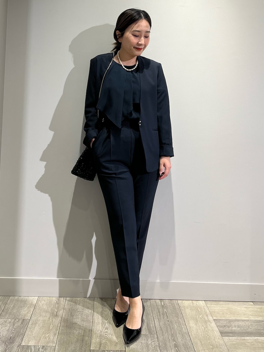 ベージュ系のノーカラーコート、ブルー系のセットアップ、ブルー系のスラックスを着用したレディースの冬コーディネートの2枚目の写真