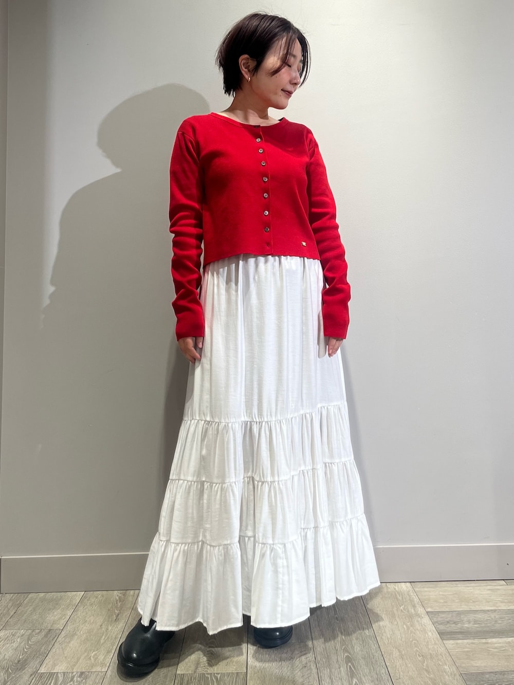 ホワイト系のスカート、ベージュ系のダウンジャケット/コート、レッド系のカーディガン/ボレロを着用したレディースの冬コーディネートの2枚目の写真