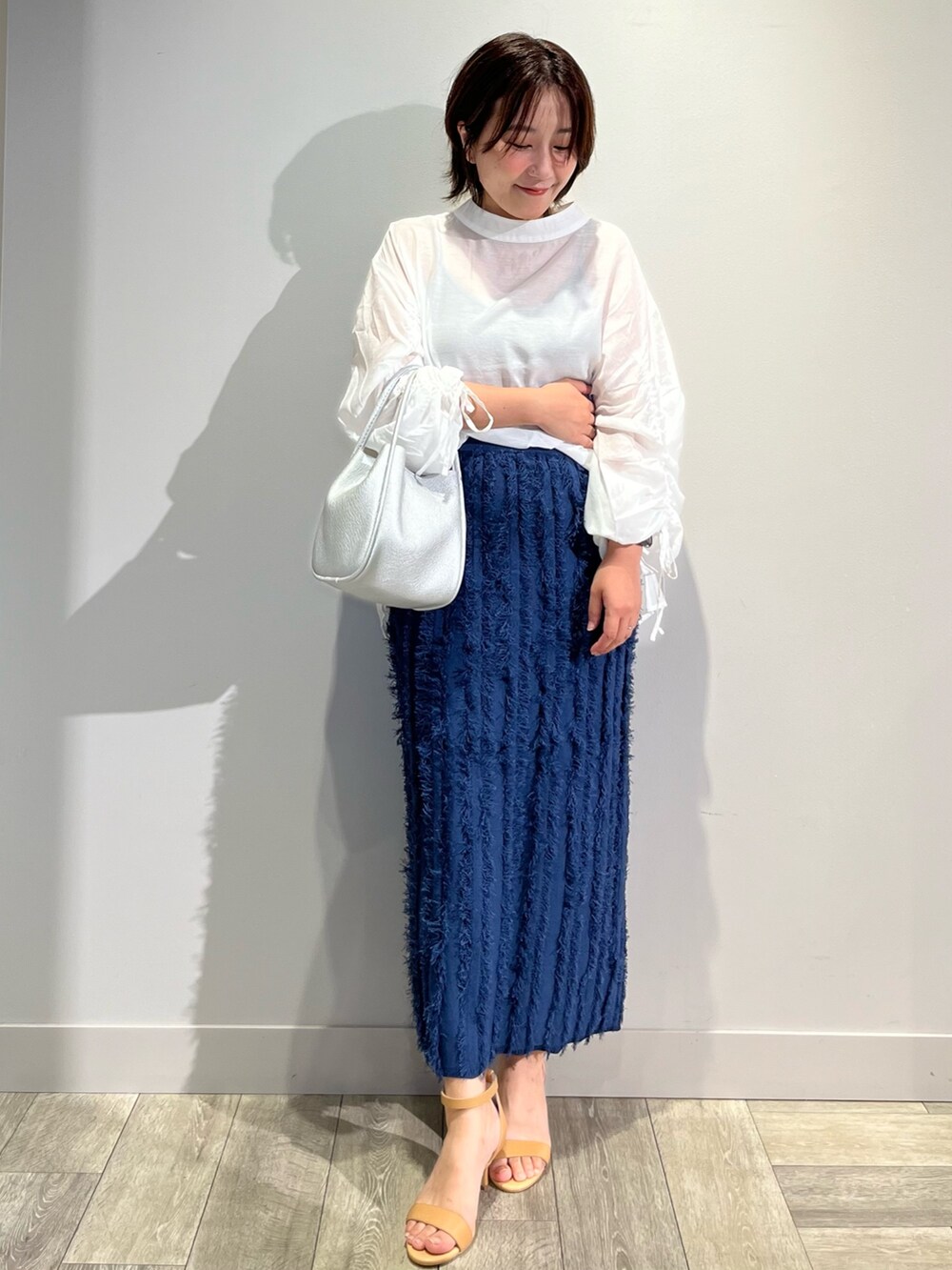 ブルー系のベスト、ブルー系のスカート、ホワイト系のシャツ/ブラウスを着用したレディースの秋コーディネートの4枚目の写真